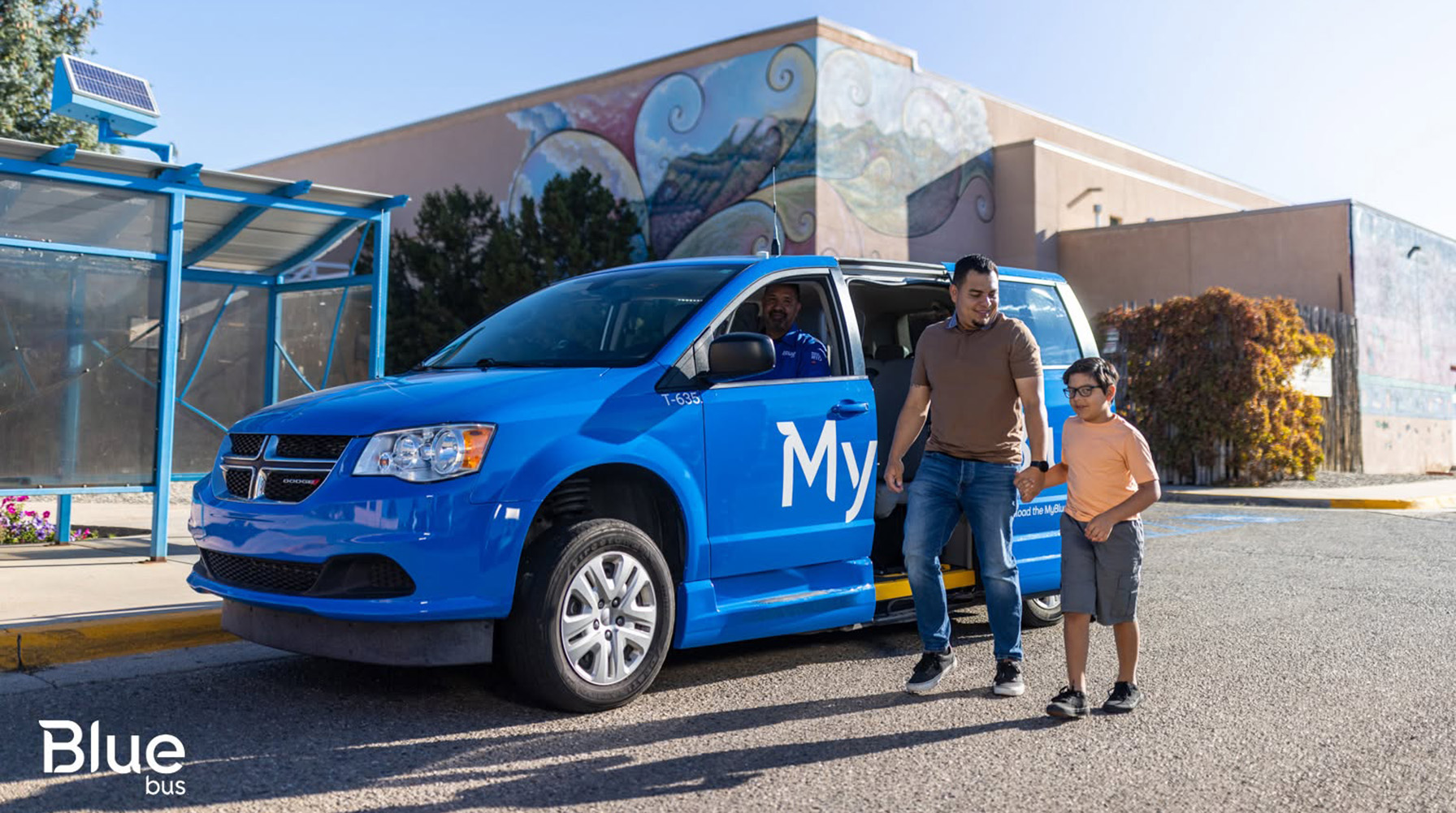 Man and child in front of a Blue Bus