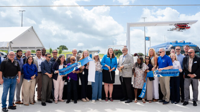 Speakers and attendees line up for the ribbon cutting.