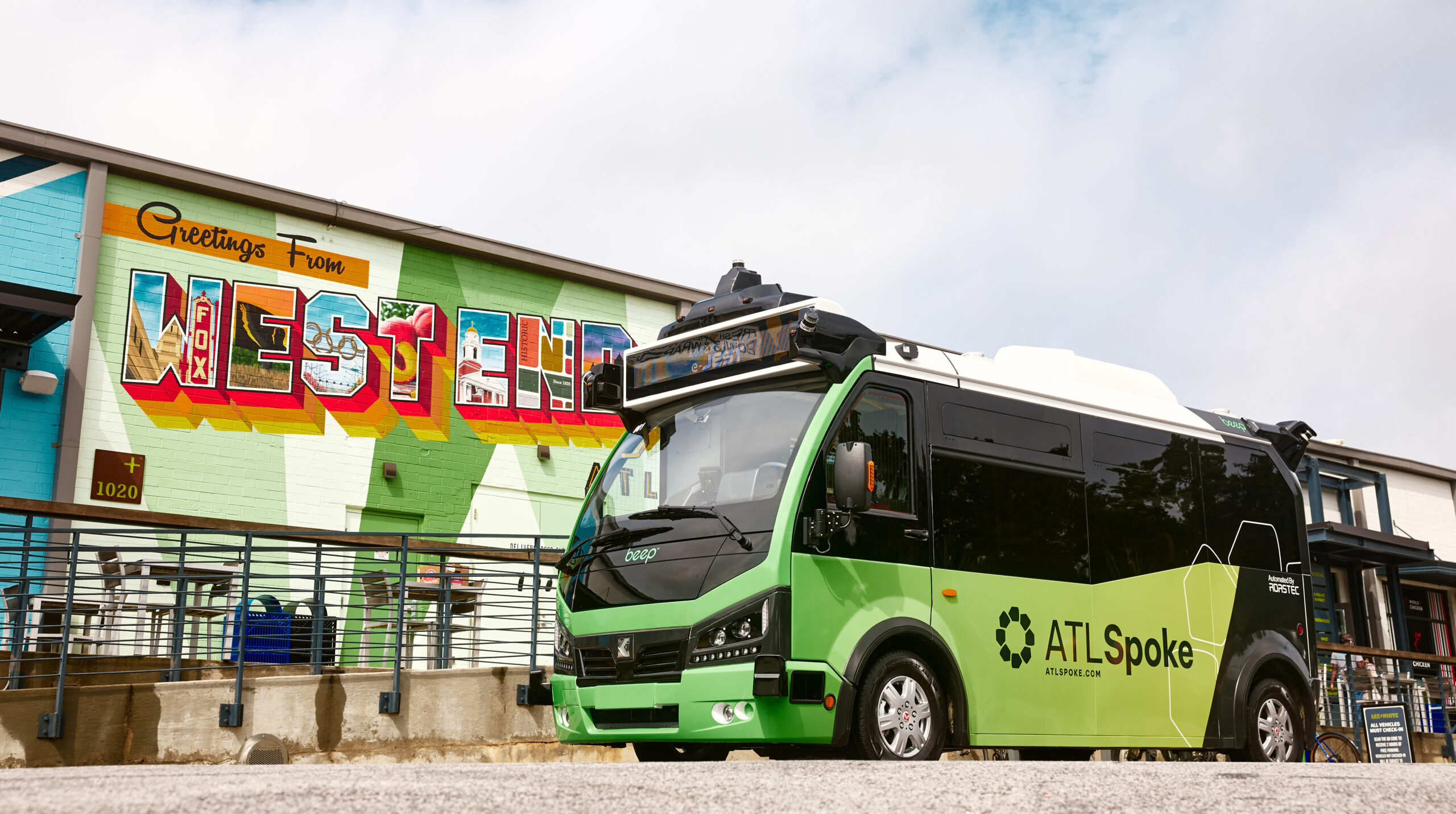 ATL Spoke bus in front of a wall painted "Greetings from West End."