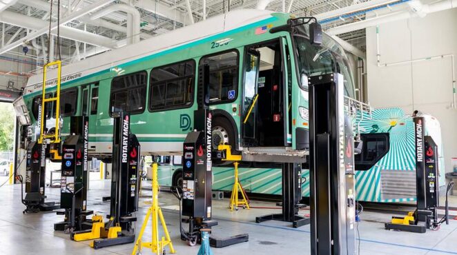 A bus on lifts in a new bright facility.