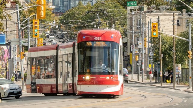 TTC streetcar traveling around a bend with a car on one side.