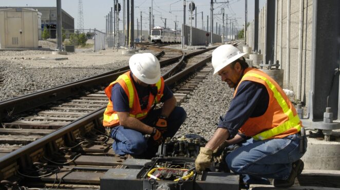 Two construction workers on a railroad.