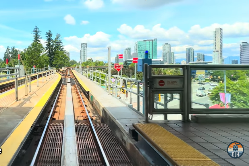 Subway tracks going towards a city, viewed from a station platform. 