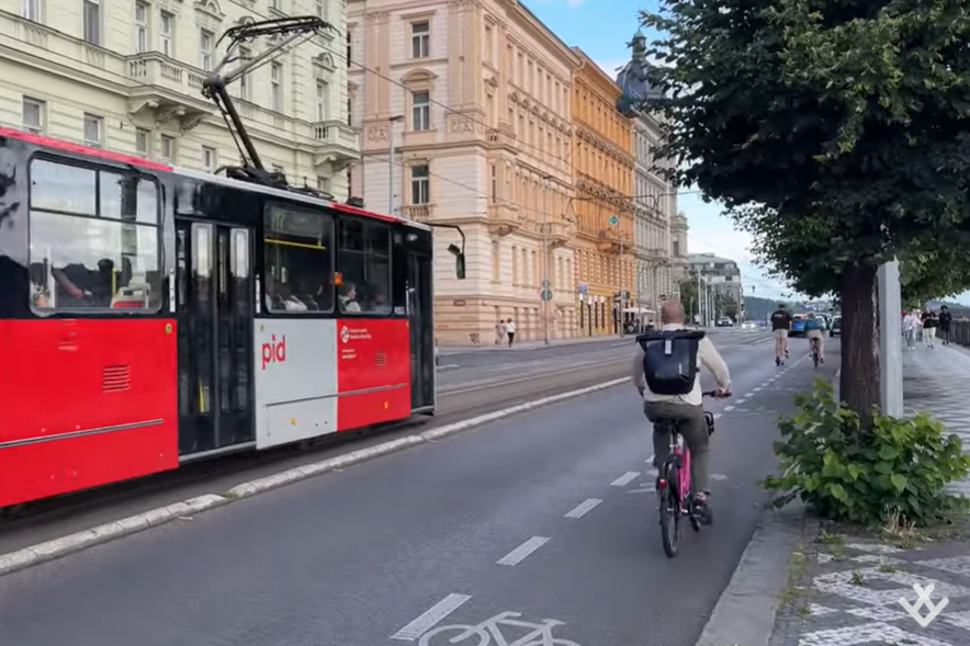 A streetcar and cyclist in a bike lane with buildings in the background. 