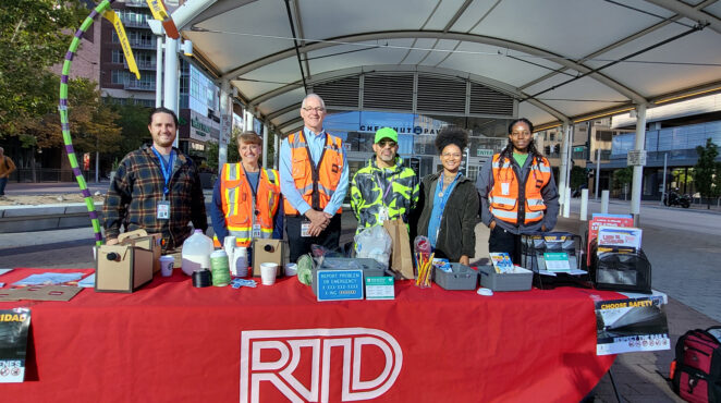 RTD staff at a table with materials outside a station.