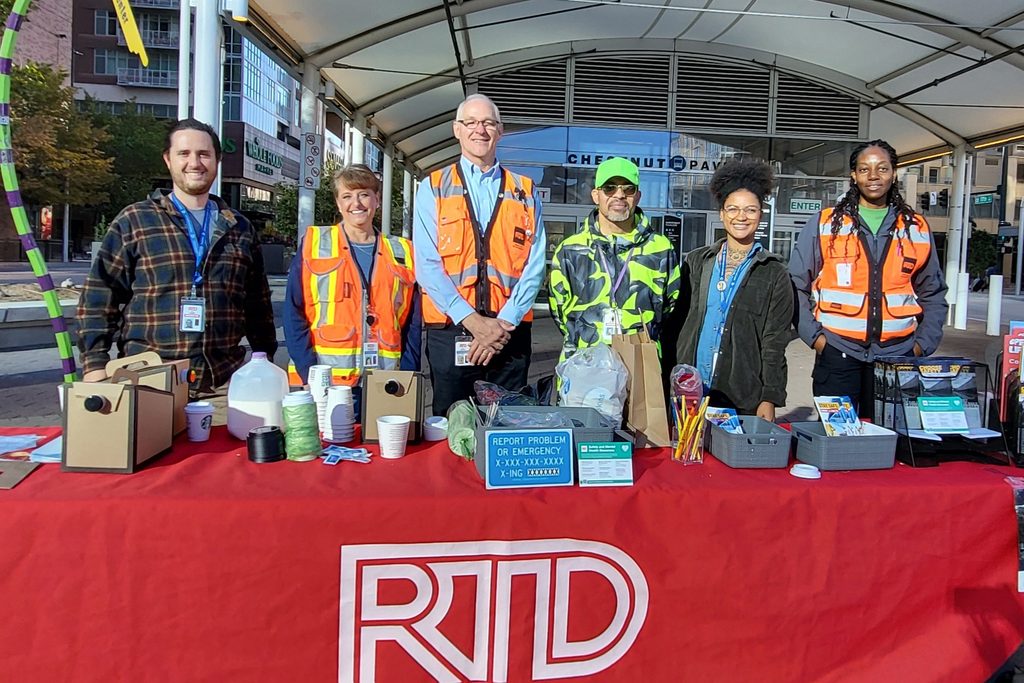 RTD staff at a table with materials outside a station.