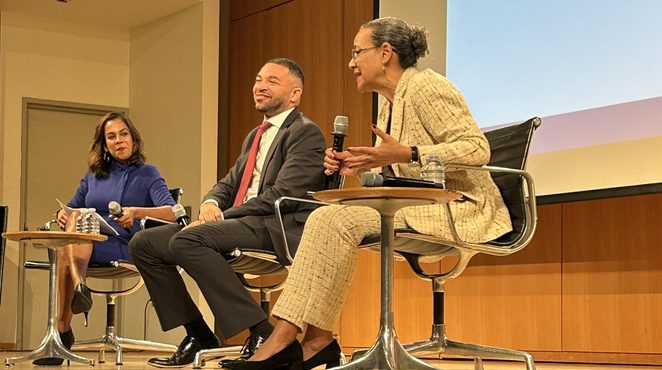 Three panelists seated on stage at an event.