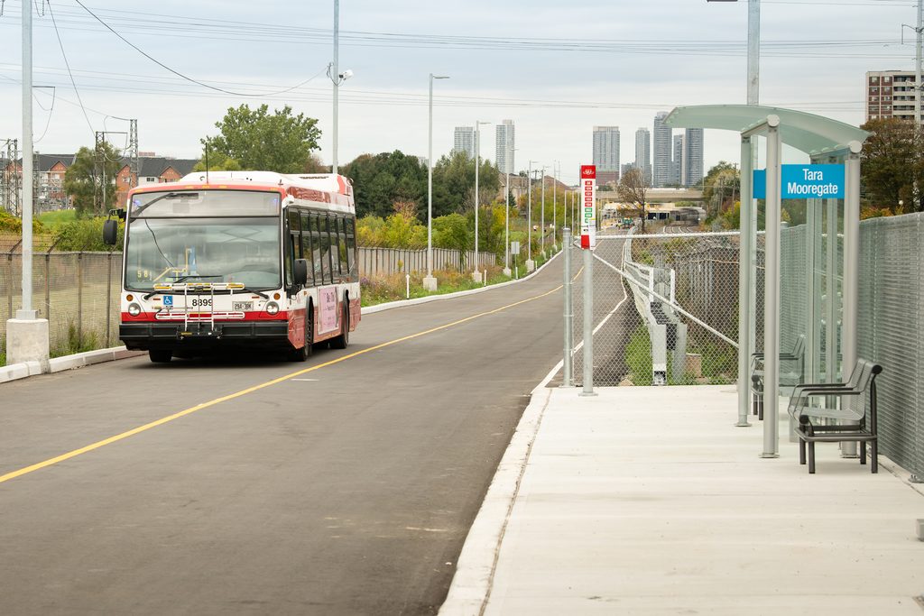 A bus on a road with skyline in the background. 