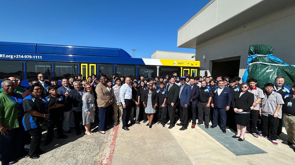 A group of staff and students pose in front of a DART bus.